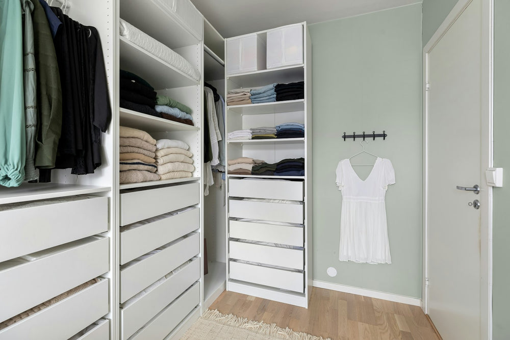 Vestidor blanco con cajones y ropa colgada